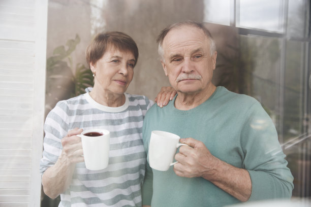 健康的老年人的生活方式。在家放松。一对老夫妇喝着茶，看着窗外图片下载