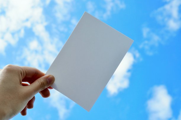 在明亮的天空和白云的背景下，一个女人拿着对角线评论空间的模型。图片下载