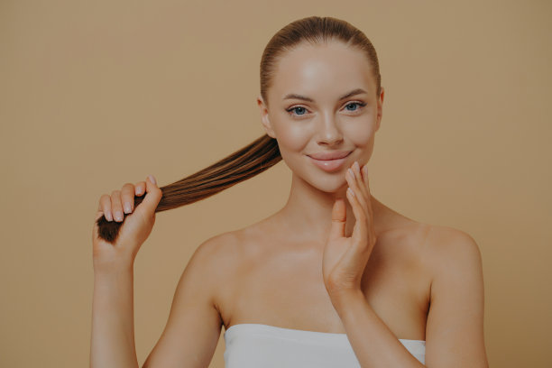 年轻自然美丽的女人触摸面部皮肤和保持头发在马尾美人肖像图片下载