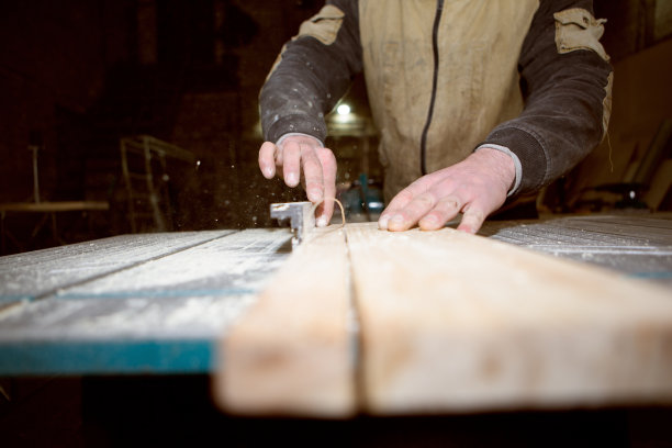 木匠在圆形机器上锯木板图片下载