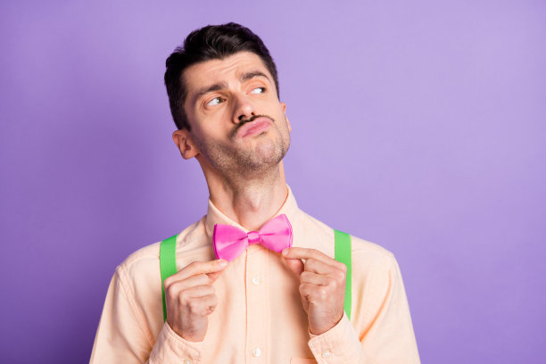 照片严肃有趣的年轻人穿着黄色衬衫双手手臂领结看空空间孤立的紫色背景图片下载