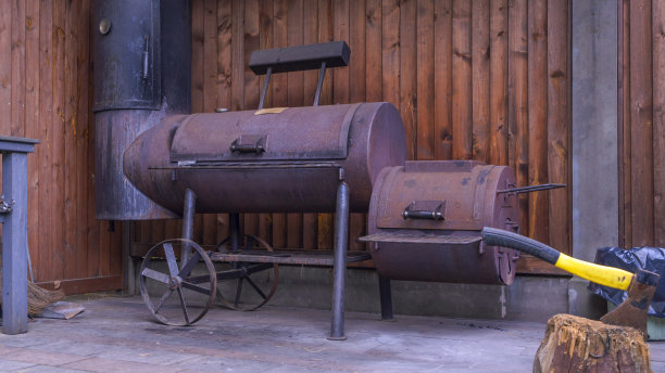 花园里的老式桶炭烧烤。老烧烤在花园外面。复古燃烧的煤炭抵消吸烟者烧烤。图片下载