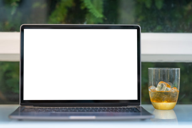 空白屏幕的笔记本电脑模型，冰咖啡放在一个玻璃杯子里，隔离在咖啡店的木制办公桌上，像背景一样，白色屏幕图片下载