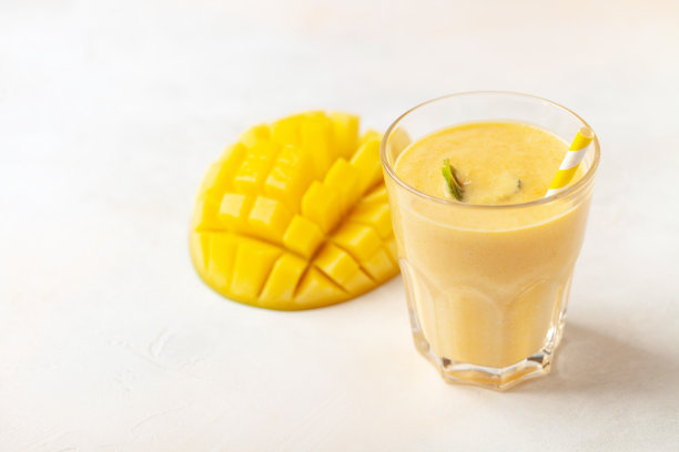 冰沙或奶昔加芒果，放在桌子上的杯子里。饮食营养图片下载