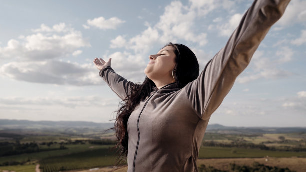 美丽的女人在山峰上张开双臂。图片下载