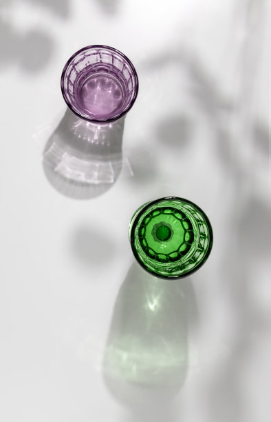 彩色装饰水杯放在白色的桌子上，阳光下有美丽的阴影，俯视图片下载