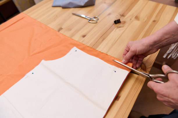 俯视图的一个时装设计师的手，裁缝，裁缝用裁缝剪刀裁剪组织附近的缝纫模式图片下载