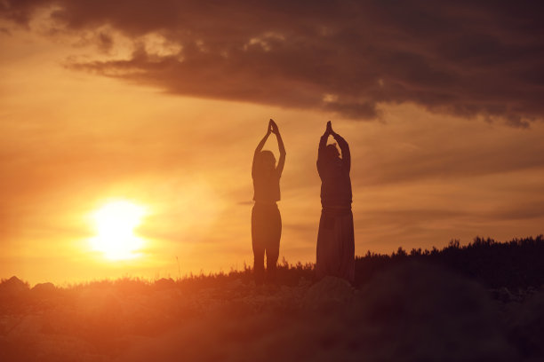 母亲和女儿一起练习瑜伽在日落日出的时间在大自然。图片下载