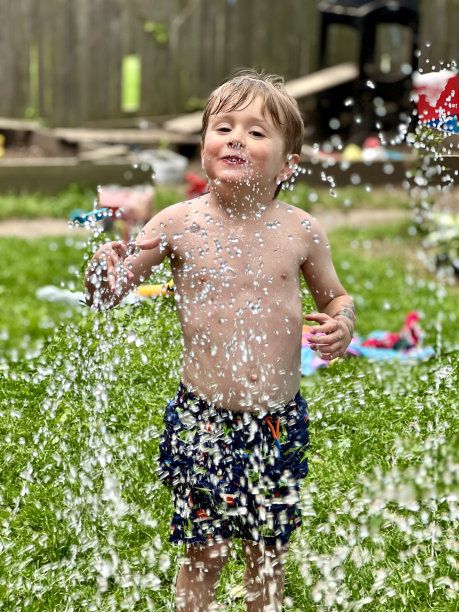 小男孩在洒水车里保持凉爽图片下载