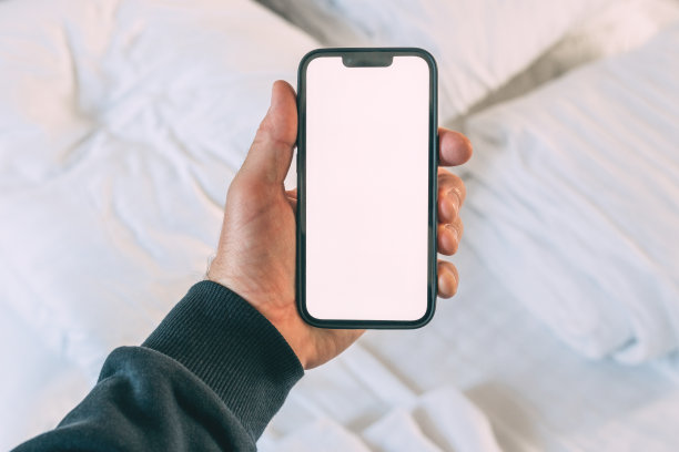 游客在酒店卧室拿着带有空白屏幕的智能手机，用于预订和预订应用程序图片下载