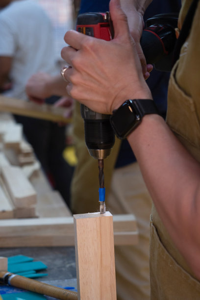 关闭了。木匠用便携式电钻在木材上钻孔。图片下载