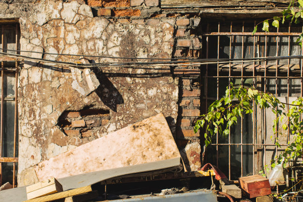 旧的枯燥乏味的纹理。摧毁了墙。窗口和电线。绿叶树图片下载