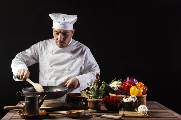 男厨师穿着白色制服，戴着帽子，用长柄大汤勺将食材倒入锅中图片下载