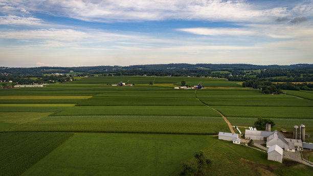 鸟瞰带谷仓和筒仓的农田，俯瞰山丘和田野图片下载