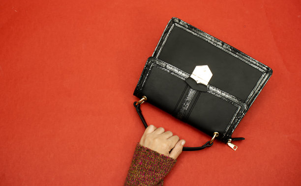 特写手拿肩包孤立的红色背景图片下载