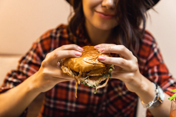 年轻女子喜欢吃汉堡，喝鸡尾酒图片下载