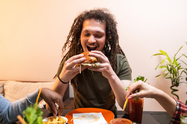 留着脏辫的年轻人吃着汉堡，喝着鸡尾酒图片下载