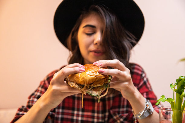 年轻女子喜欢吃汉堡，喝鸡尾酒图片下载