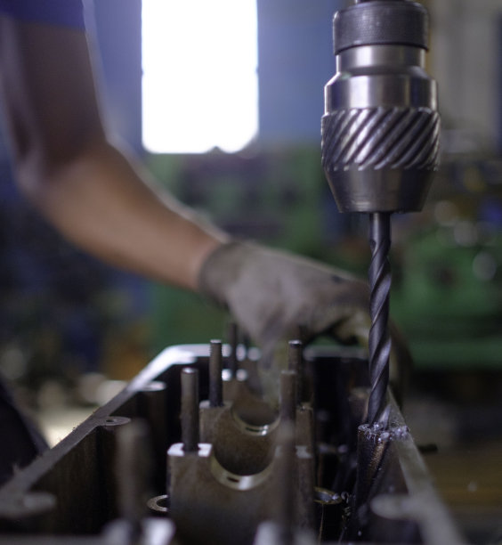 家庭车间里戴着手套用垂直钻工作的白人技术员。图片下载