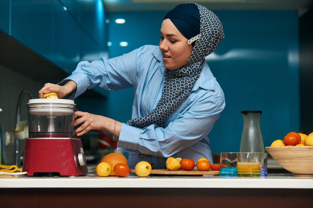 阿拉伯妇女在现代厨房里做果汁。家的概念。健康的生活方式的概念。有选择性的重点。高质量的照片图片下载