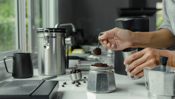 咖啡粉放在不锈钢勺子上用手将烘培好的意式浓缩咖啡倒入用设备工具冲泡的意大利摩卡壶中，准备咖啡图片下载