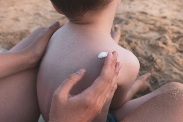 在沙滩上涂抹防晒系数高的防晒霜，护肤概念图片下载