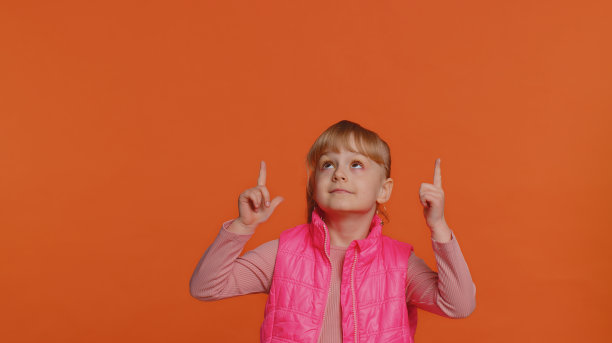 蹒跚学步的孩子女孩竖起大拇指，指着空的地方，为文字、标志的广告区域图片下载