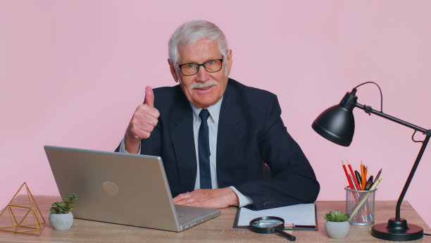 资深商务人士竖起大拇指，同意、批准，喜欢在粉色办公室使用笔记本电脑的好消息图片下载