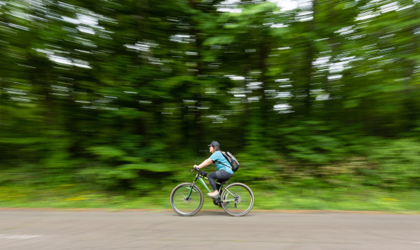 女子山地车骑穿过森林道路图片下载