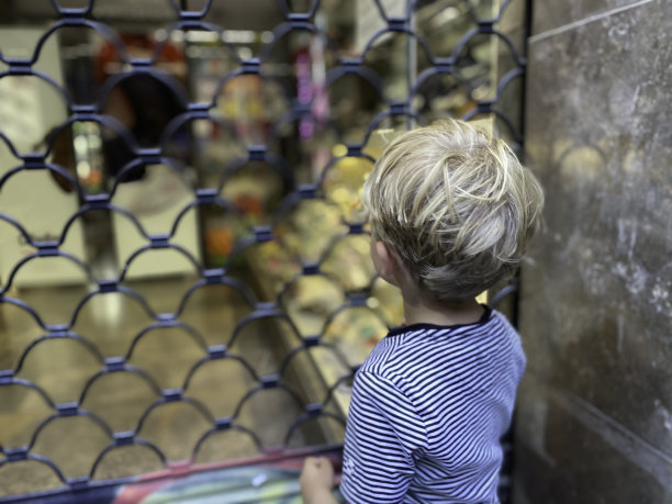 蹒跚学步的孩子看着商店橱窗图片下载