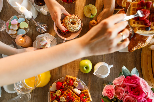 享用美味的早餐时，手伸向盘子里的食物图片下载