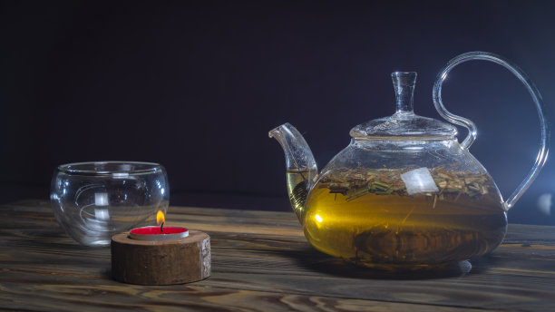 热凉茶在玻璃茶壶在木制桌子上的黑色背景。传统的草本饮料。放置文字或设计。图片下载