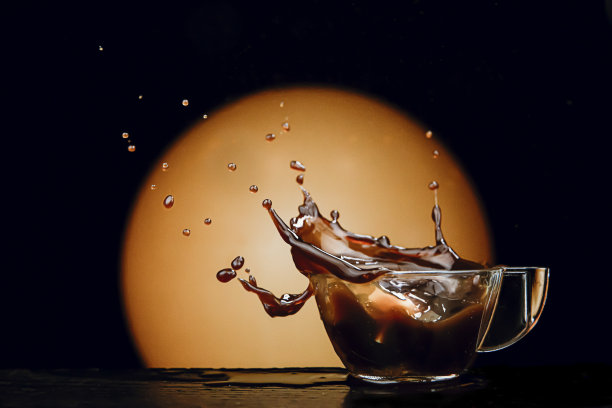当一块糖落在黑暗温暖的背景上时，咖啡飞溅在杯子里图片下载