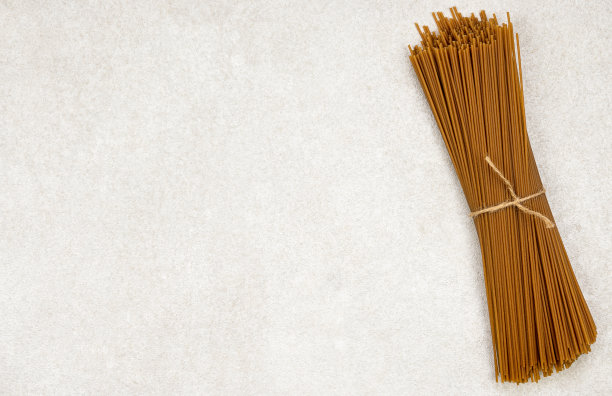 一束棕色的长意大利面在灰色的背景上复制空间图片下载