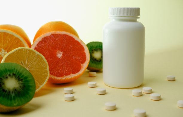 维生素。医学概念。药房或自然。白色的瓶子里装着维他命，药片。多汁的成熟柑橘片。柠檬。橙色。葡萄柚。猕猴桃。图片下载