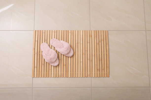 木制垫子和拖鞋铺在瓷砖地板上，俯视图。浴室配件图片下载