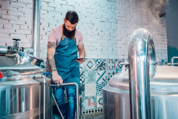 在啤酒厂工作的男子，正在使用用于发酵过程的药片应用程序图片下载