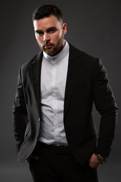 一个穿着黑色西装和白色衬衫的英俊男子。商人站在黑色背景上图片下载