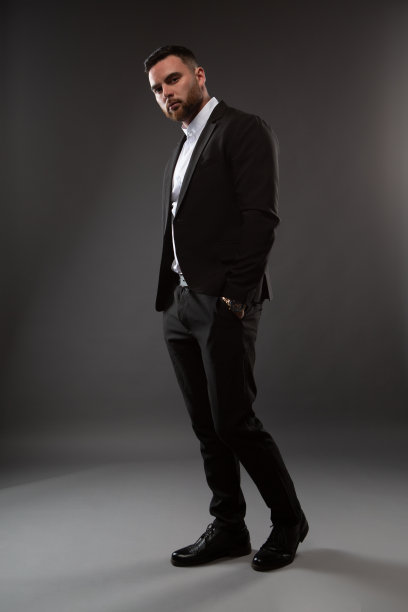 一个穿着黑色西装和白色衬衫的英俊男子。商人站在黑色背景上图片下载