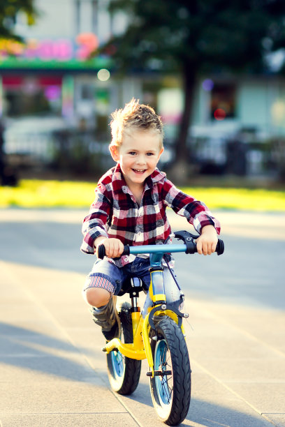 穿着衬衫和牛仔裤的时髦欧洲男孩在柏油路上骑平衡自行车。儿童不戴头盔骑马图片下载