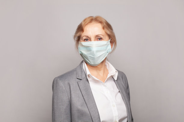 医生、医务工作者或医生，成熟的妇女在医学口罩上灰色的墙壁横幅背景图片下载