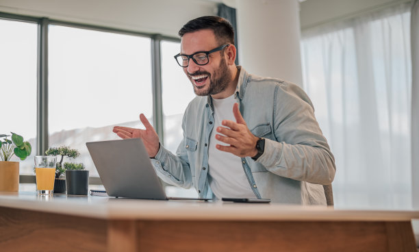 快乐的男性专业的手势，而看着笔记本电脑在办公室的桌子上图片下载