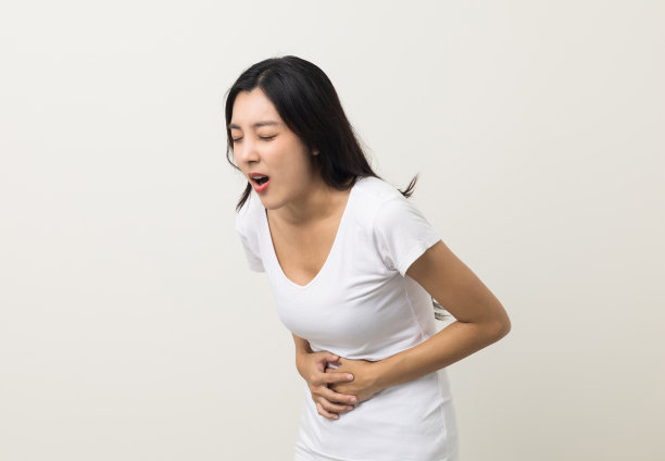 一名妇女胃痛和胃炎。她把她的手放在她的肚子上，挤压它放松和安慰。她今年25岁，有痛经。拍摄于孤立的白色背景。图片下载