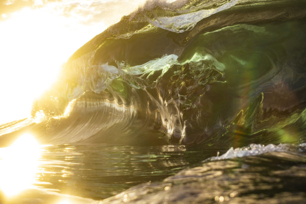 巨大而有力的海浪涌上浅浅的礁石平台，发出明亮的金色光芒图片下载