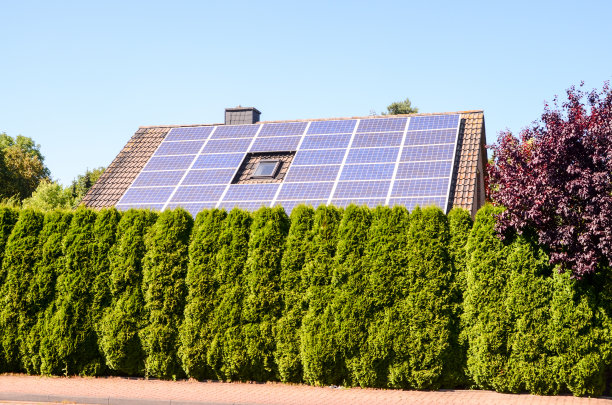 太阳能发电厂在房子前面，数码照片图片作为背景图片下载