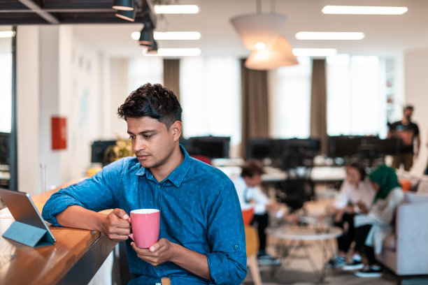 休闲商务男人在办公室休息区使用电脑喝茶图片下载