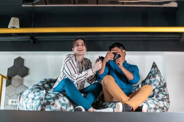 努力工作，尽情玩乐：创意创业办公室休息区，男女工人在休息时玩电脑游戏图片下载