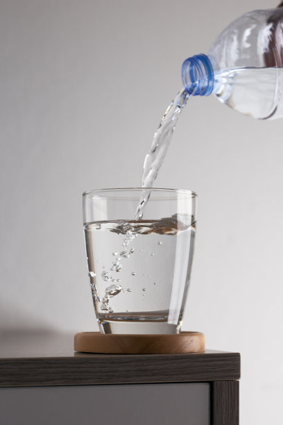 水从木桌上的玻璃塑料瓶中倾泻而出图片下载