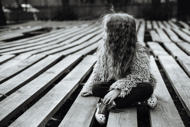 小可爱的女孩肖像与长卷发。在室外的花园里。时髦的学龄前儿童坐在公园里的木托盘上。文本。黑白照片图片下载