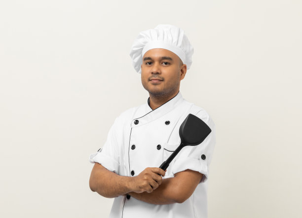 年轻英俊的亚洲男子厨师在制服与特纳厨房用具站在孤立的背景各种姿态行动。厨师职业厨师在厨房、餐厅和酒店工作。图片下载